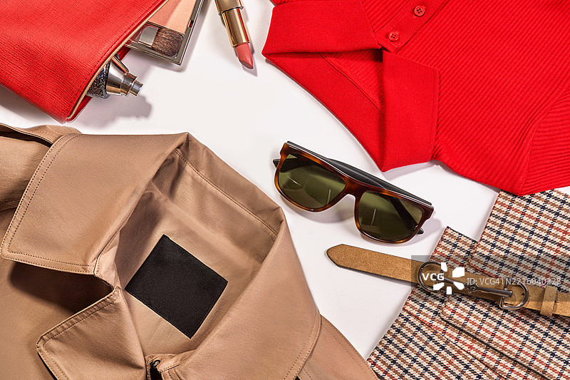时尚服装系列，包括流行的时尚服装和太阳镜，适合女性的化妆品，颜色为棕色、卡其色、米色和红色，搭配红色长袖毛衣。图片素材