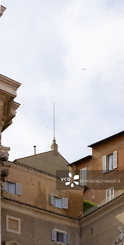 一座历史悠久的烟囱高耸于梵蒂冈的屋顶之上，标志着新教皇的选举，周围是永恒的建筑和在罗马天空下翱翔的鸟儿。图片素材
