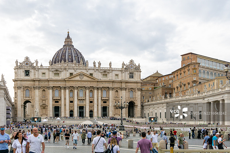 梵蒂冈的圣彼得大教堂，文艺复兴建筑的杰作，周围是一群热闹的游客在晴朗的天空下探索圣彼得广场的宏伟。图片素材