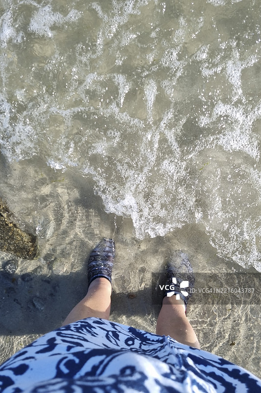 穿着水鞋和沙滩服装的人在初夏勇敢地迎接寒冷的海水图片素材