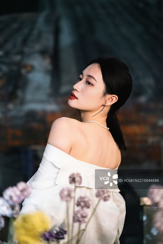 佩戴珍珠项链的迷人女性，面带柔和表情，浪漫的灯光下摆姿势。图片素材