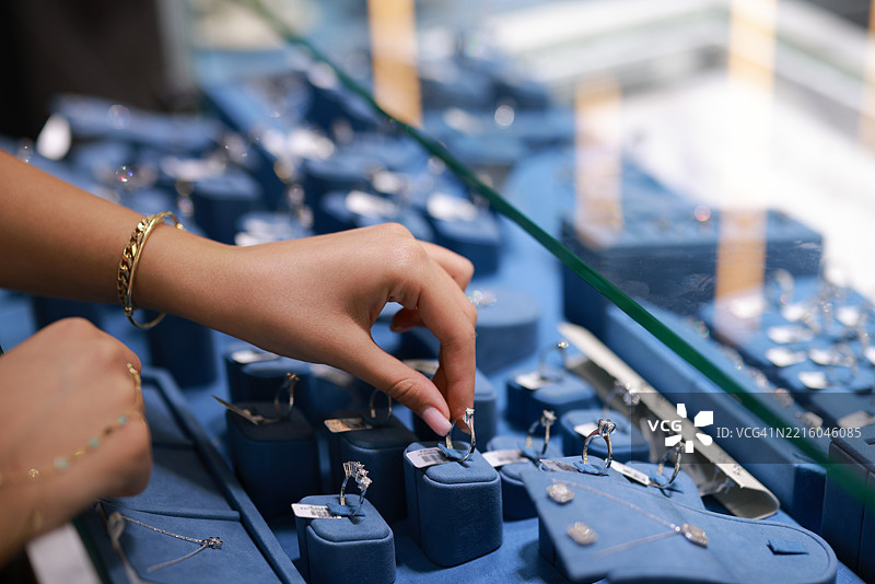 珠宝店的女店员拿出柜台上的珠宝，准备向顾客介绍。图片素材