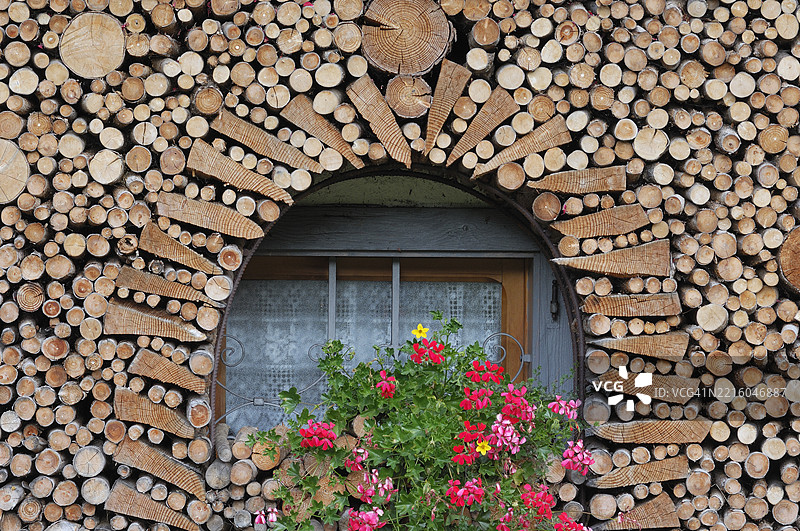 窗边堆放着木材，周围盛开着鲜花。意大利，威尼托，贝卢诺省，杜洛米蒂山脉，欧洲。图片素材