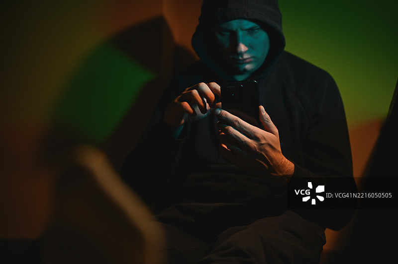 黑客在黑暗的房间里使用智能手机入侵安全系统图片素材