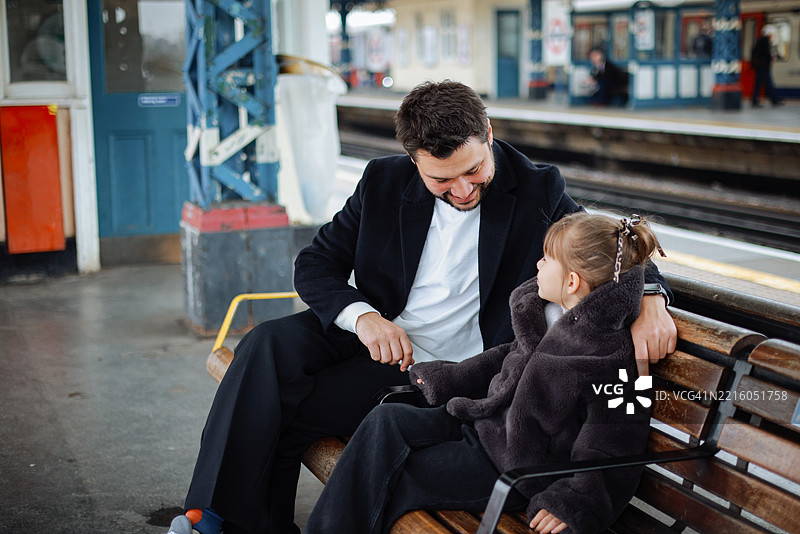 微笑的小女孩和她的父亲在火车站月台上等待快车图片素材