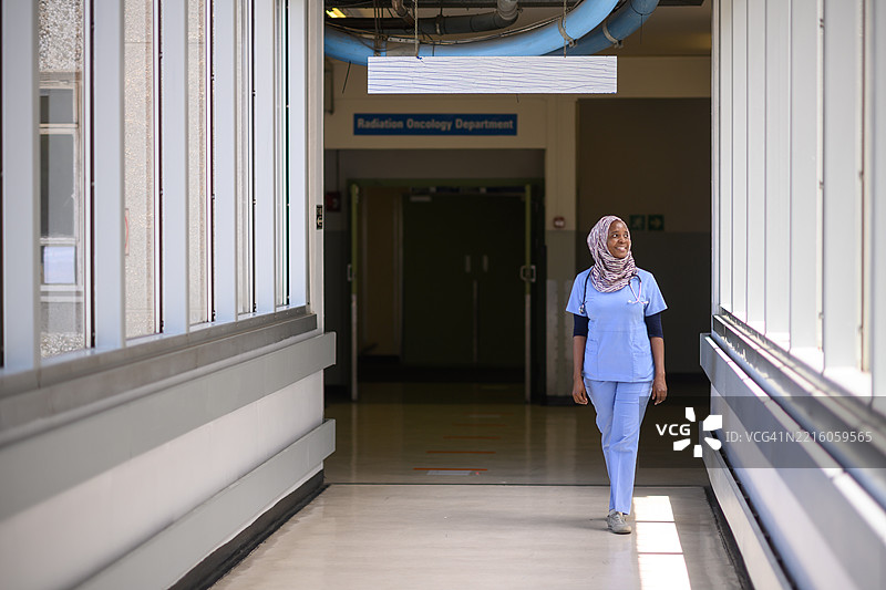 自信的女性医护人员走在明亮的医院走廊中图片素材