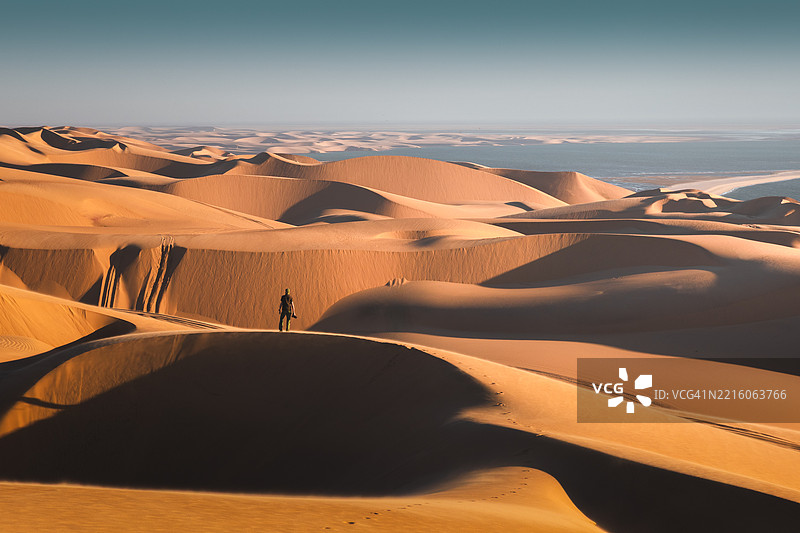 旅行者在纳米比亚的日落时分探索广阔而壮丽的沙丘图片素材
