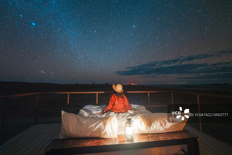 游客坐在户外的床上，仰望星空图片素材
