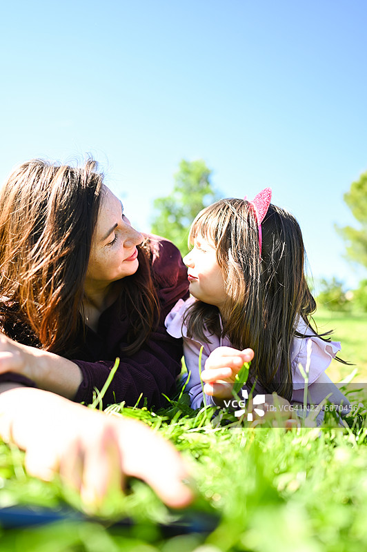 母女俩躺在草地上，共享温馨的户外时光图片素材