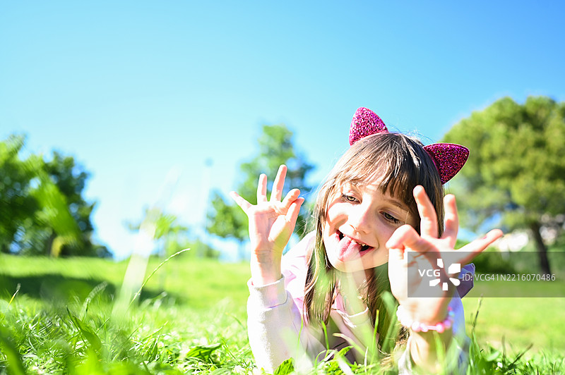 顽皮的孩子在阳光明媚的日子里躺在草地上吐舌头图片素材