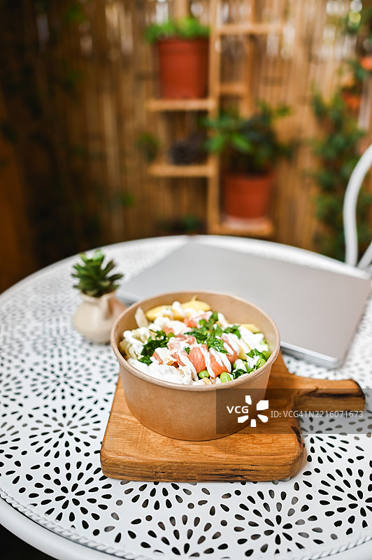 餐厅花园桌子上的三文鱼波奇碗和笔记本电脑图片素材