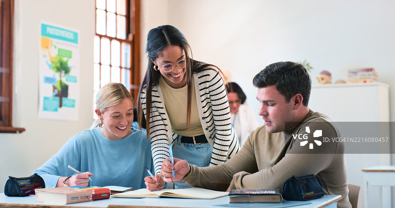 年轻学生在明亮的教室环境中与友好的老师合作图片素材