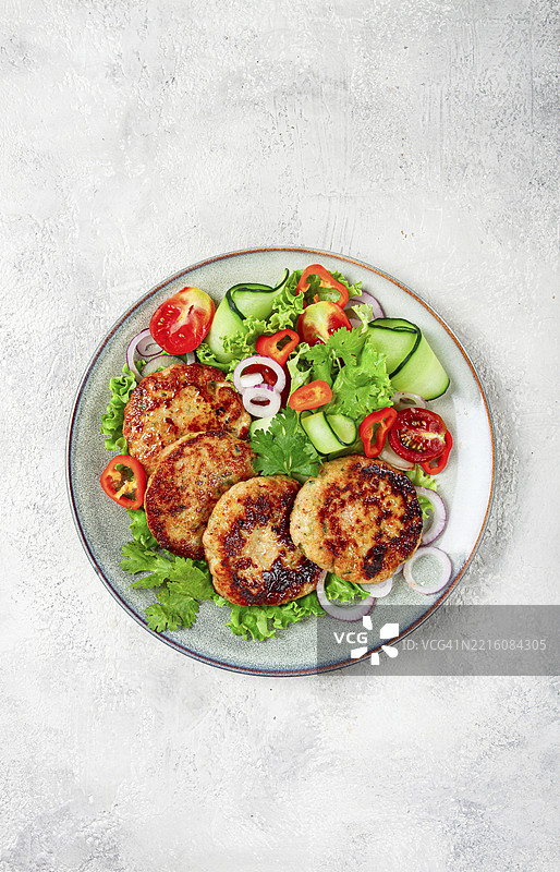 炸鸡肉排，剁碎的鸡肉，配有蔬菜，灰色背景，搭配蔬菜沙拉，俯视图，自制，无人。图片素材