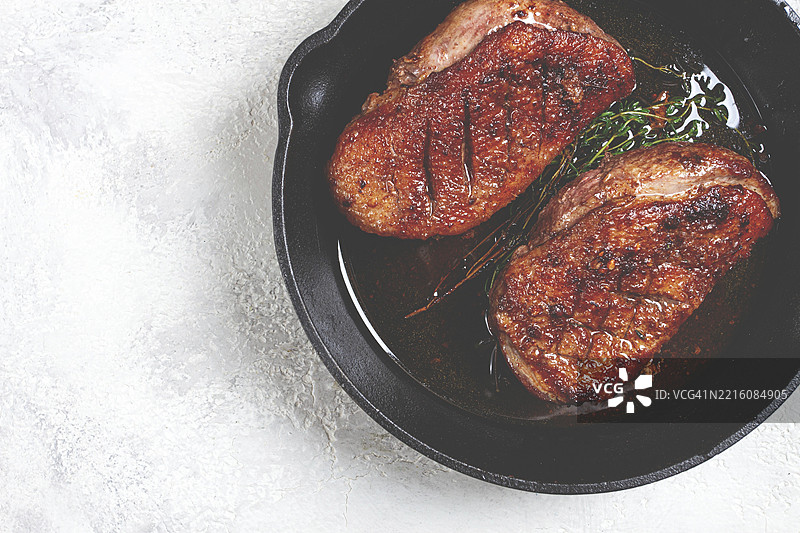 香料和草药煎制的烤鸭胸肉特写，锅中，无人。图片素材