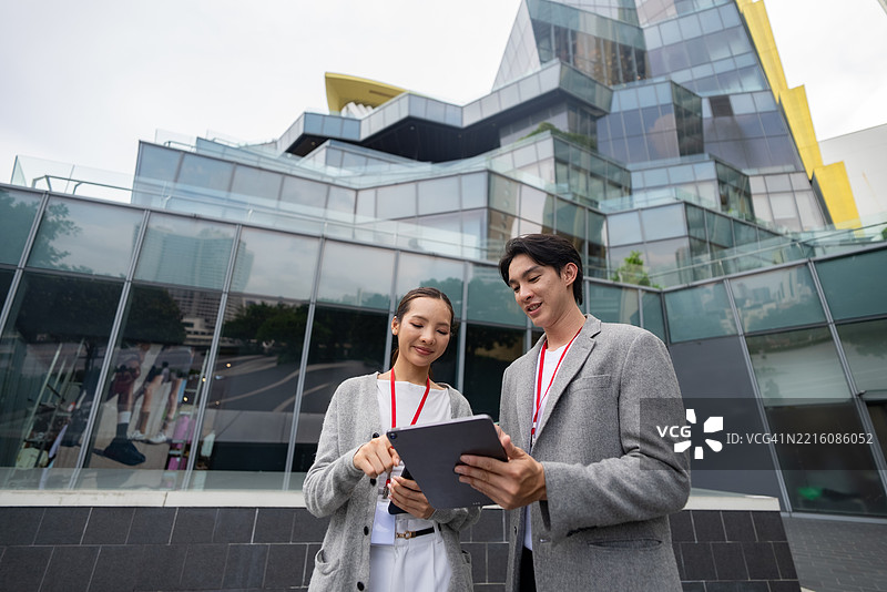 两位自信的商务人士穿过繁忙的城市，展现出现代领导力的活力。图片素材