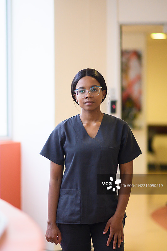 年轻的医学生穿着医务服，自信地站在医院走廊里图片素材
