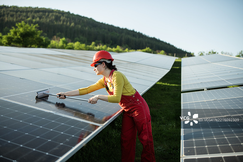 女性工作人员在日落时清洁光伏面板。图片素材