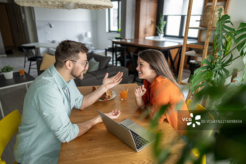 年轻情侣在家吃早餐时交谈并做手势图片素材