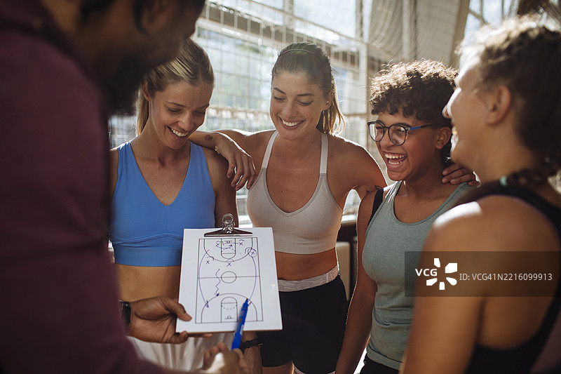 微笑的女篮球队与教练在室内图片素材