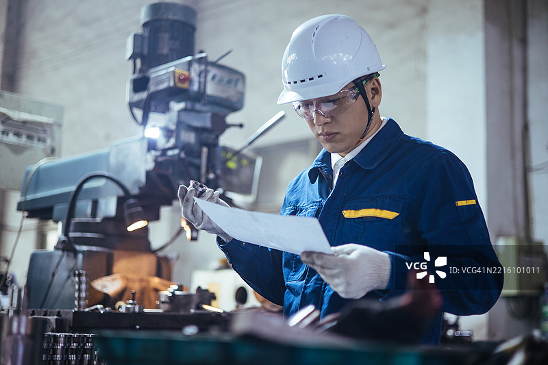 一位亚洲工程师在车间研究蓝图图片素材