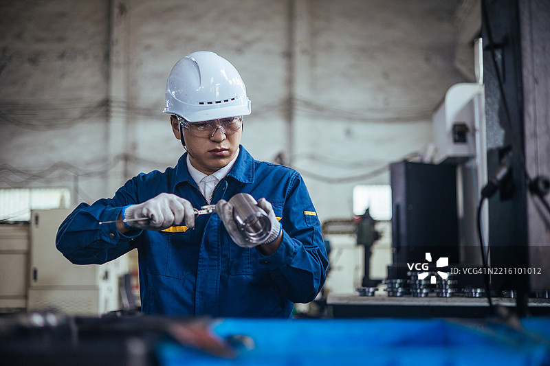 男性工程师正在使用游标卡尺测量钢制工件。图片素材