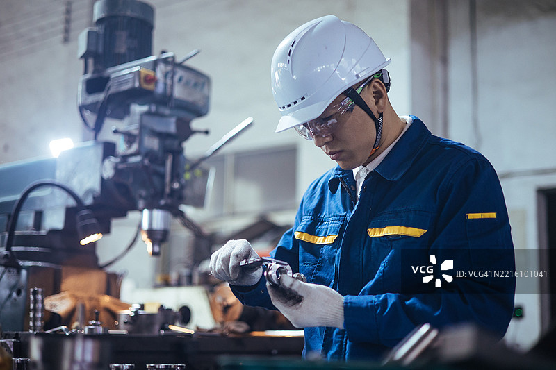 男性工程师正在使用游标卡尺测量钢制工件。图片素材