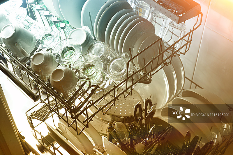 打开的洗碗机，托盘已移除，内部背光照明图片素材