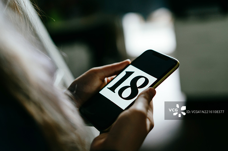 特写镜头显示一个人手持的手机，屏幕上显示数字18图片素材