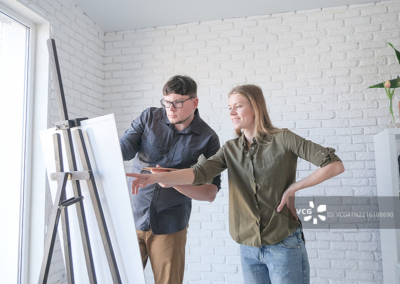 艺术家夫妇在画布上作画，手持油画刷和调色板。图片素材