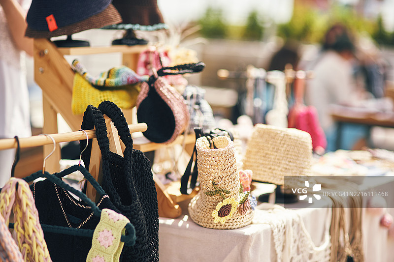 阳光明媚的户外市场展示的手工包和帽子图片素材