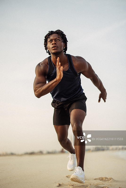 在晨练时，一名运动员在沙滩小径上奔跑图片素材