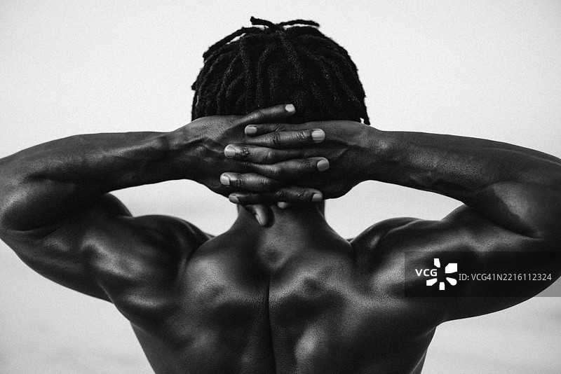 肌肉发达的身材，强壮的背部，双手交叉在头后。图片素材