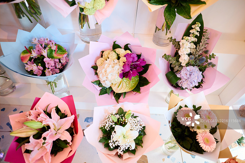 色彩缤纷的花束用柔和色调的纸包裹，陈列在白色的架子上，营造出一种生动而愉快的展示。图片素材