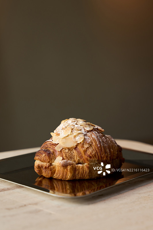 美味的刚出炉的杏仁可颂面包，上面撒有糖霜，放在托盘上图片素材