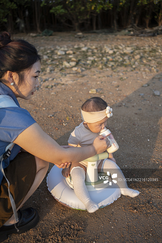 母亲在海滩上喂养她的宝宝图片素材