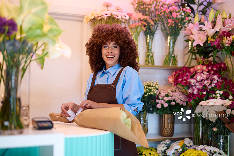 年轻的花店老板在花店里准备花束并微笑图片素材