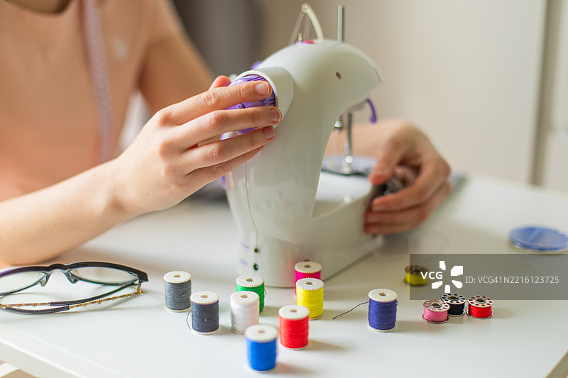 女性在缝纫机上缝制织物的中部特写图片素材
