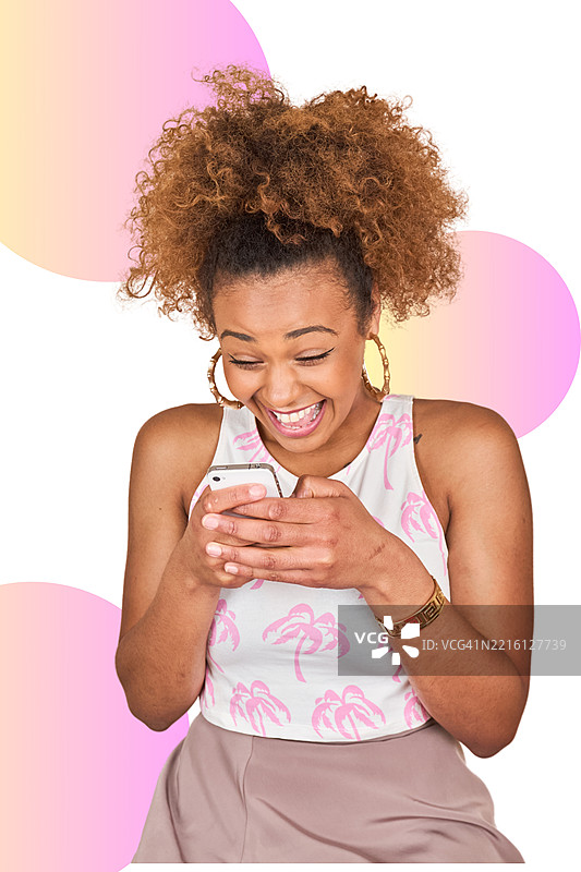 微笑的Z世代女性在粉彩色块背景前对着智能手机大笑图片素材