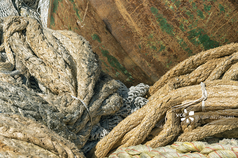 前景中有生锈的锅炉部件，背景是电缆绳和渔网。图片素材