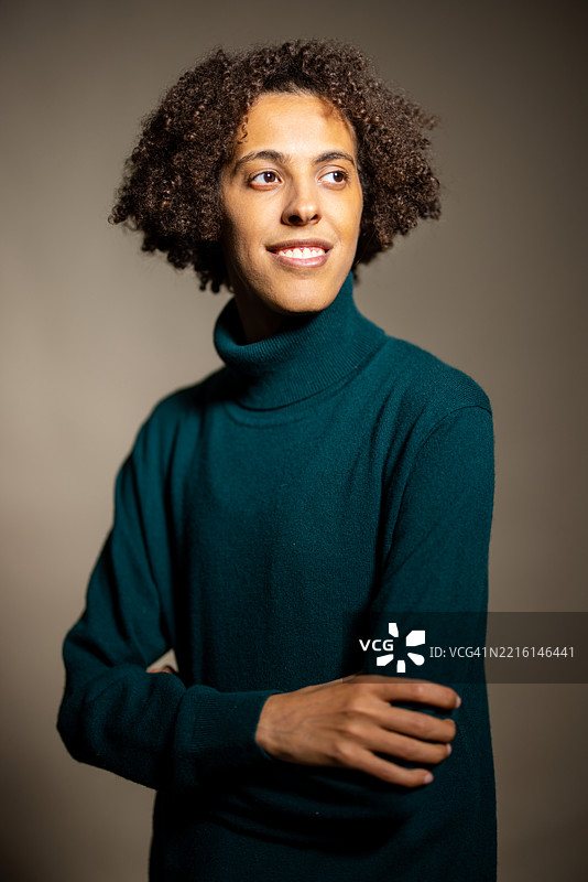 穿着绿色毛衣的男子在工作室微笑着望向一旁图片素材