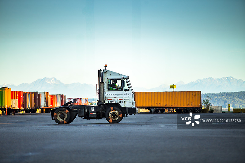 阳光明媚的日子里，华盛顿塔科马港背景中的半挂卡车与集装箱图片素材