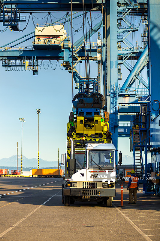 塔科马港阳光明媚的日子里，货车在集装箱码头装卸集装箱的垂直静态图。图片素材