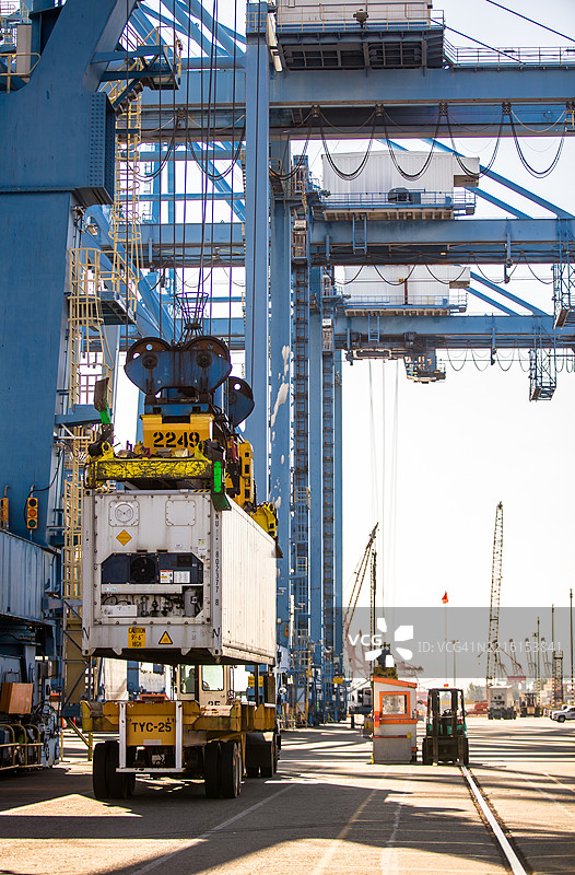 在华盛顿州塔科马的集装箱码头，集装箱被跨式搬运车吊起 - 静态照片图片素材