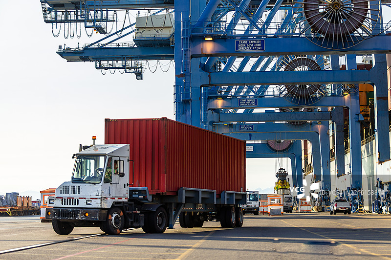 塔科马港的门式起重机下停放着红色集装箱的货车图片素材