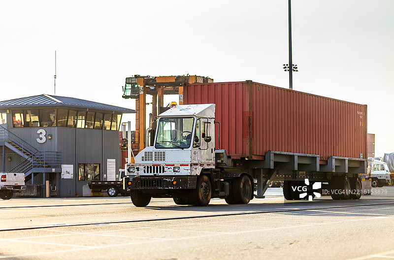 在华盛顿州塔科马港，阳光明媚的日子里，一辆货车正在运输红色集装箱。图片素材