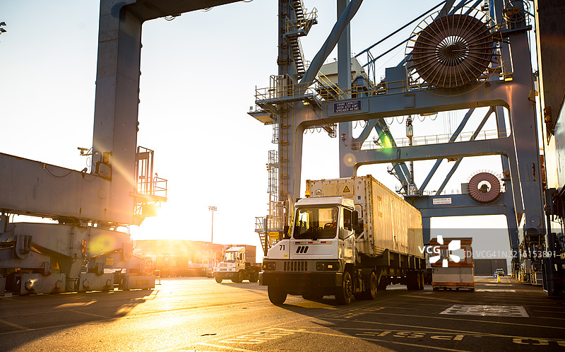 在华盛顿州塔科马的集装箱码头，夕阳下的货车运输白色集装箱图片素材