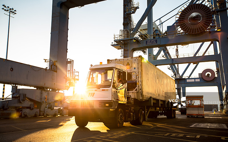 在华盛顿州塔科马的集装箱码头，夕阳下的货车运输白色集装箱图片素材