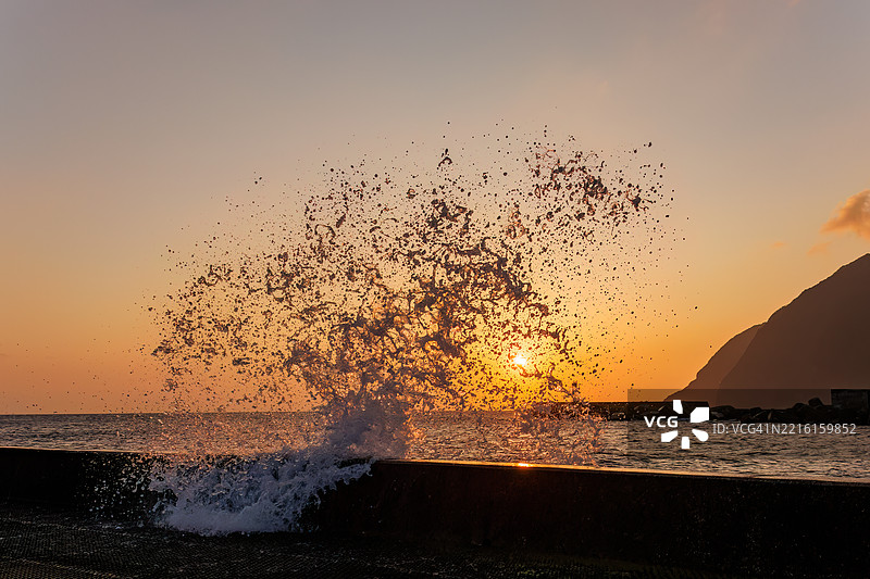 太平洋的汹涌波涛沐浴在八丈岛的晨光中。清晨时分，底港和底港海滩的日出。图片素材