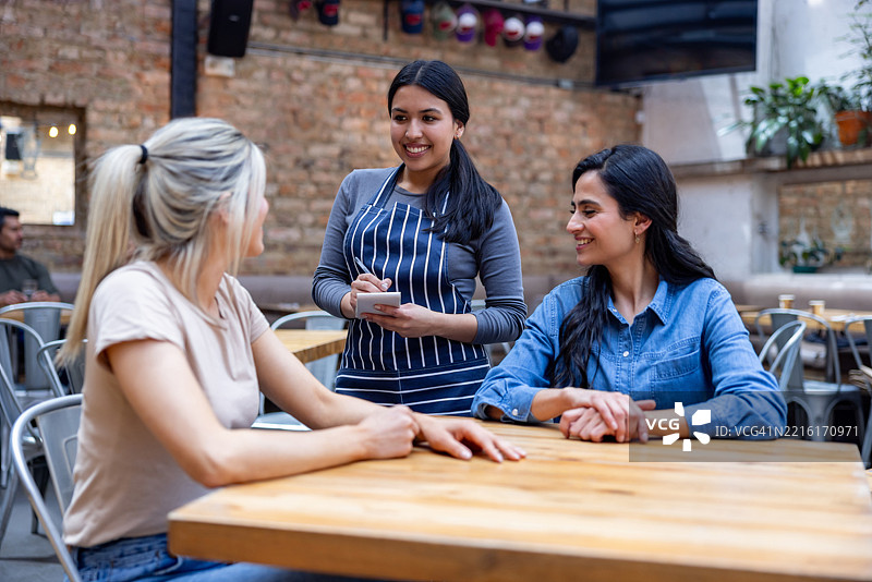 女服务员在餐厅为两位女士点餐图片素材