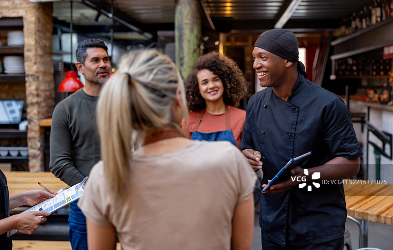 快乐的厨师在餐厅与一群员工开会交谈图片素材